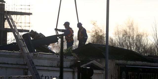 December 1, 2013: Scottish Fire and Rescue services look on at a section of the helicopter being lifted from the scene following the helicopter crash at the Clutha Bar in Glasgow, Scotland. (AP Photo)