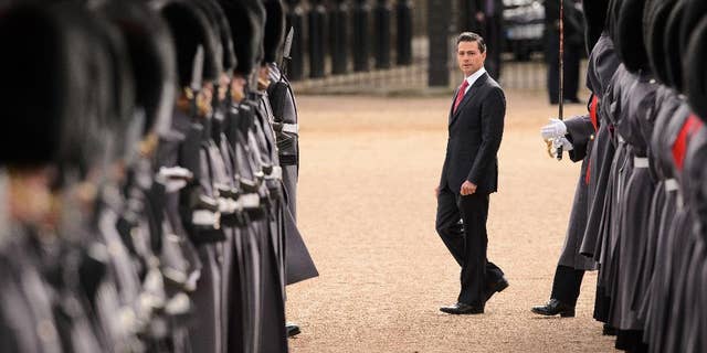 Mexican President Enrique Pena Nieto, centre, inspects a Guard of Honour during a ceremonial welcome in central London on Tuesday March 3, 2015. The President and his wife are on a 3 day state visit to Britain. (AP Photo/Loen Neal, Pool)