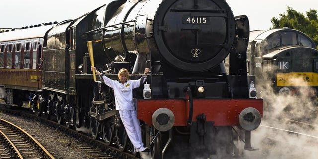 June 20, 2012: Josephine Loughran carrying the Olympic Flame on the Scots Guardsman steam locomotive as they make the journey from York to Thirsk in England on day 33 of the torch relay (AP Photo/Ben Birchall, LOCOG, HO)