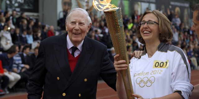 July 10, 2012: The Olympic Flame is passed between Sir Roger Bannister and Oxford doctoral student Nicola Byrom on the running track at Iffley Road Stadium in Oxford, England.