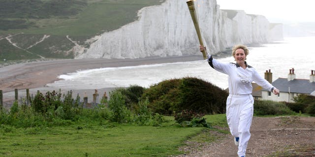 July 17, 2012: This image made available by LOCOG shows Kathy Gore, running with the Olympic Flame at Seaford Head, with a view of the Seven Sisters cliffs, southern England.