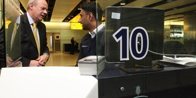 May 1, 2012: Britain's Immigration Minister Damian Green, left, talks to UK Border Agency Immigration officer Shafait Ali during a visit to Terminal 3 of Heathrow Airport, London. Green says that the government is taking action to address long waits at airport immigration lines amid further criticism from an airline executive.