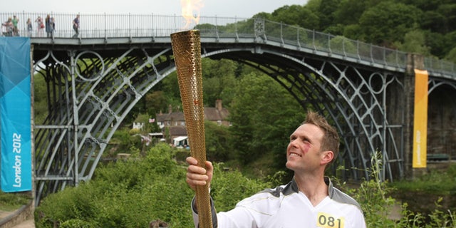 Lyndon Flavell holds the Olympic Flame next to the Iron Bridge at Ironbridge Gorge between Much Wenlock and Telford in central England.