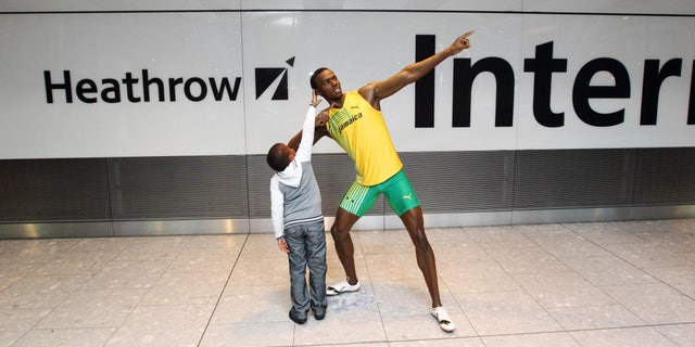 July 12, 2012: A child reaches up to touch the wax figure of Usain Bolt, as passengers arrive at London's Heathrow Airport Terminal 5, are greeted by the wax figure.