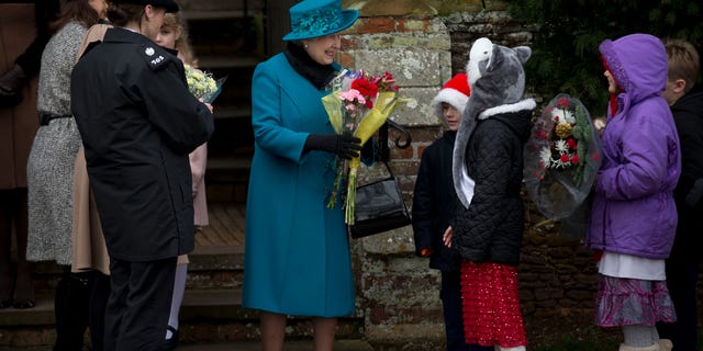 British Queen Elizabeth II smiles as she receives flowers from children after attending the traditional Christmas Day church service in Sandringham, England.