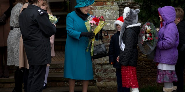 Britain's Queen Elizabeth II smiles as she receives flowers from children after attending the traditional Christmas Day church service in Sandringham, Inghilterra.