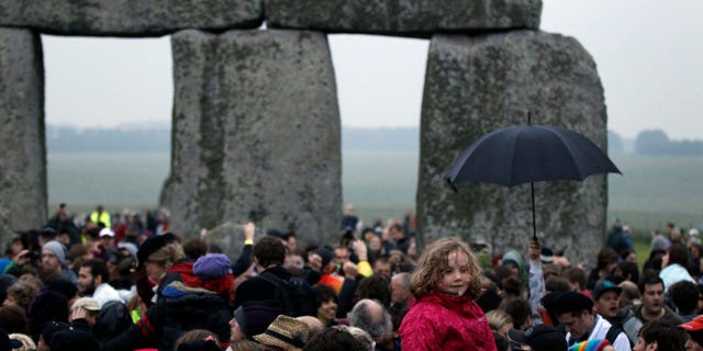 People gather during the summer solstice at Stonehenge, near Salisbury Thursday, June 21, 2012. Rain-sodden crowds welcomed a spectacularly rainy summer solstice at Stonehenge in true British fashion Thursday: With stoicism and wit. But through the wind and rain, drummers inside the ancient stone circle kept up their thumping rhythm, new age pagans kept up their chaotic dance, and visitors kept up their sense of humor. (AP Photo/Lefteris Pitarakis)