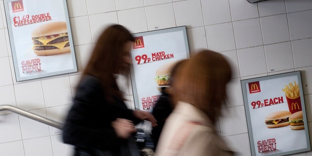 April 30, 2012: Three women walk past an advert for McDonald's fast food restaurant products in London.