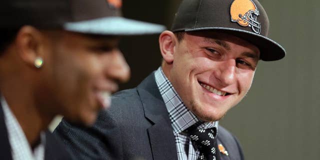 Cleveland Browns quarterback Johnny Manziel, right, from Texas A&M, watches cornerback Justin Gilbert during their introductory news conference at the NFL football team's facility in Berea, Ohio Friday, May 9, 2014. The Browns selected Gilbert with the eighth pick and Manziel with the 22nd pick in the first round of Thursday night's draft. (AP Photo/Tony Dejak)