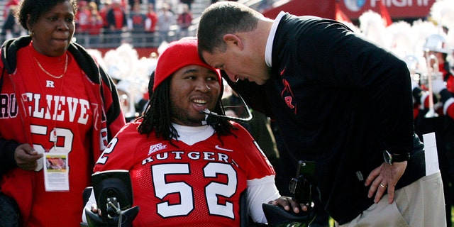 Nov. 19, 2011: In this file photo, paralyzed former Rutgers football player Eric LeGrand, center, is greeted by coach Greg Schiano, right, before an NCAA college football game against Cincinnati in Piscataway, N.J.