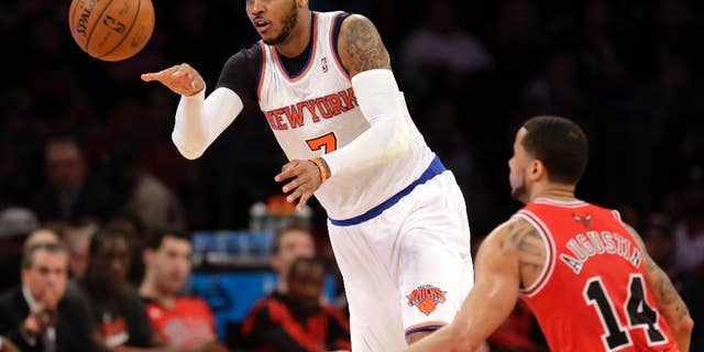 New York Knicks' Carmelo Anthony, left, passes the ball past Chicago Bulls' D.J. Augustin during the first half of the NBA basketball game, Sunday, April 13, 2014 in New York. The Knicks defeated the Bulls 100-89. (AP Photo/Seth Wenig)