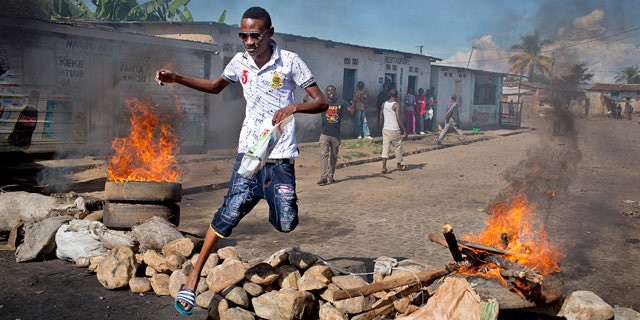 May 14, 2015: A civilian jumps over a burning barricade of rocks erected by residents to protect themselves from police in a northern district of Bujumbura, the capital of Burundi. (AP Photo/Erik Esbjornsson)