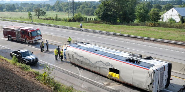 Emergency personnel work the scene where a Greyhound bus bound for St. Louis from New York City flipped on its side on the Pennsylvania Turnpike, briefly trapping a woman and injuring about two dozen people, according to authorities, about one mile east of the Lancaster-Lebanon interchange, early Saturday, Aug. 13, 2011, near Manheim, Pa.
