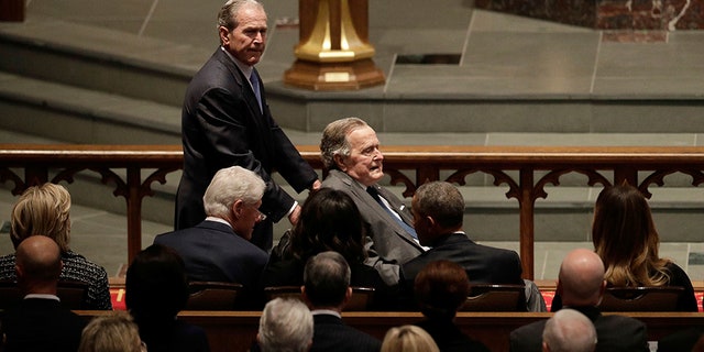 Former President George W. Bush pushes his father former President George H.W. Bush at former first lady Barbara Bush's funeral.