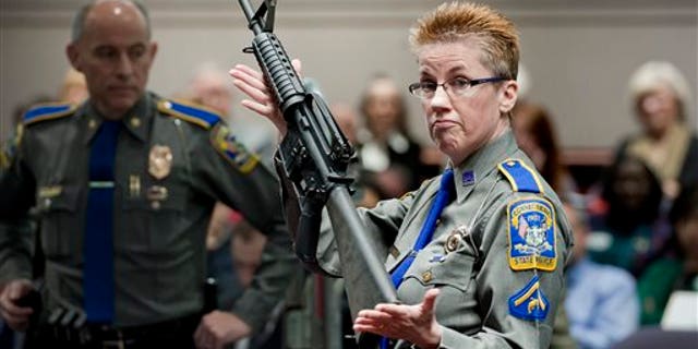 In this Jan. 28, 2013, file photo, firearms training unit Detective Barbara J. Mattson, of the Connecticut State Police, holds up a Bushmaster AR-15 rifle, the same make and model of gun used by Adam Lanza in the Sandy Hook School shooting, for a demonstration during a hearing of a legislative subcommittee reviewing gun laws, at the Legislative Office Building in Hartford, Conn.