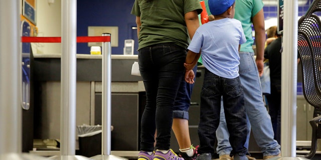 Immigrants from El Salvador who entered the country illegally stand in line at a bus on July 7, 2015.