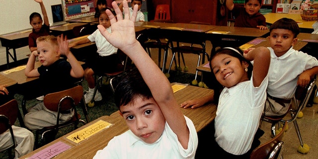 TYLER,TX - SEPTEMBER 11:  Monolingual Hispanic students raise their hands to answer a question during a class taught in Spanish at Birdwell Elementary School September 11, 2003 in Tyler, Texas. The first grade students spend half their school day learning reading, writing, and arithmetic in Spanish and the other half learning them in English. Birdwell, a school of 600 students, 60 percent of them Hispanic with a significant portion of them Spanish speakers, requires a dual-language curriculum for it?s kindergarten and first graders.  (Photo by Mario Villafuerte/Getty Images)