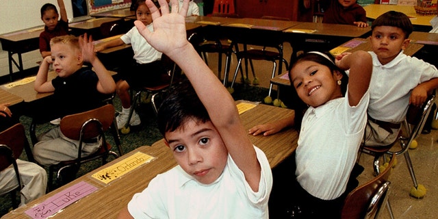 TYLER,TX - SEPTEMBER 11: Monolingual Hispanic students raise their hands to answer a question during a class taught in Spanish at Birdwell Elementary School September 11, 2003 in Tyler, Texas. The first grade students spend half their school day learning reading, writing, and arithmetic in Spanish and the other half learning them in English. Birdwell, a school of 600 students, 60 percent of them Hispanic with a significant portion of them Spanish speakers, requires a dual-language curriculum for it?s kindergarten and first graders. (Photo by Mario Villafuerte/Getty Images)