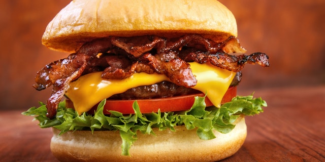 Bacon burger with beef patty on red wooden table