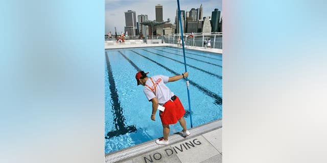 A lifeguard cleans the water at a swimming pool located on a barge anchored on Brooklyn's waterfront.