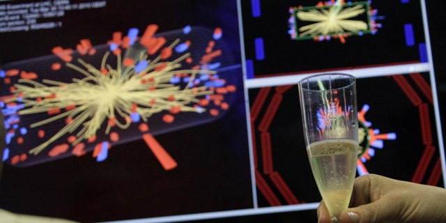 A scientist holds a glass of champagne after the first successful collisions at full power at the Compact Muon Solenoid (CMS) experience control room at the Large European Organisation for Nuclear Research (CERN) in Meyrin, near Geneva March 30, 2010.