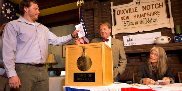 CORRECTS TO DIXVILLE NOTCH FROM DIXVILLE NOTCHE AND CLARIFIES VOTES- Dixville Notch's first voter Clay Smith drops his ballot into the box as moderator Tom Tillotson watches Tuesday, Nov. 8, 2016, in Dixville Notch, N.H. Dixville Notch, where the nation's first voters cast their ballots on Election Day, had Democratic presidential candidate Hillary Clinton beating Republican Donald Trump. (AP Photo/Jim Cole)