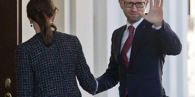 CORRECTS PHOTOGRAPHER TO PABLO MARTINEZ MONSIVAIS Ukraine Prime Minister Arseniy, right, waves as he is greeted by US acting Chief of Protocol Natalie Jones, left, during his arrival at the White House in Washington, Thursday, March 13, 2014. Arseniy is meeting with Vice President Joe Biden before traveling to New York to visit the United Nations. (AP Photo/Pablo Martinez Monsivais)