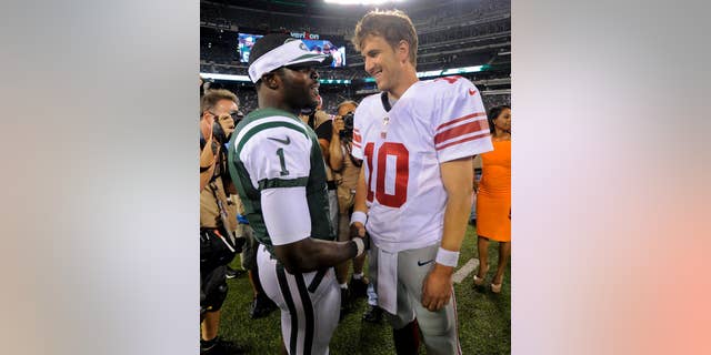 CORRECTS DAY AND DATE - New York Jets quarterback Michael Vick (1) talks with New York Giants quarterback Eli Manning (10) after a preseason NFL football game, Friday, Aug. 22, 2014, in East Rutherford, N.J. The Giants won 35-24. (AP Photo/Bill Kostroun)