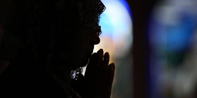 CORRECTS THE NUMBER OF THE VICTIMS- A Catholic offers prayers at an early morning mass to pay respect to the victims of the Nagasaki atomic bombing at the Urakami Cathedral in Nagasaki, southern Japan Sunday, Aug. 9, 2015. Ceremony for the 70th anniversary of the atomic bombing will start late this morning. The atomic bomb attack on this city that left more than 70,000 dead and hastened the end of World War II exactly 70 years ago.(AP Photo/Eugene Hoshiko)