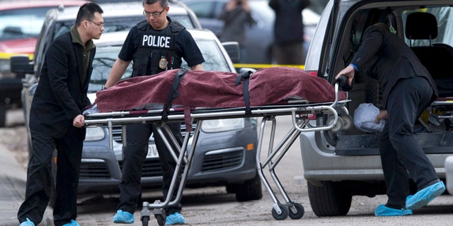 April 15, 2014: Police remove a body from the scene of a multiple fatal stabbing in northwest Calgary, Alberta.