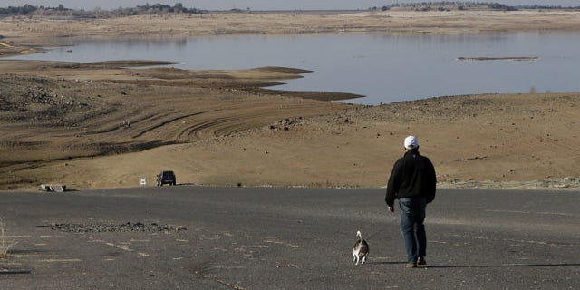 FILE -- In this Jan. 9, 2014 file photo a visitor to Folsom Lake, Calif., walks his dog down a boat ramp that is now several hundred yards away from the waters edge, in Folsom, Calif. Gov. Jerry Brown was governor the last time California had a drought of epic proportions, in 1975-76 and now is pushing a controversial $25 billion plan to build twin tunnels to ship water from the Sacramento-San Joaquin River Delta to farmland and cities further south. (AP Photo/Rich Pedroncelli,file)