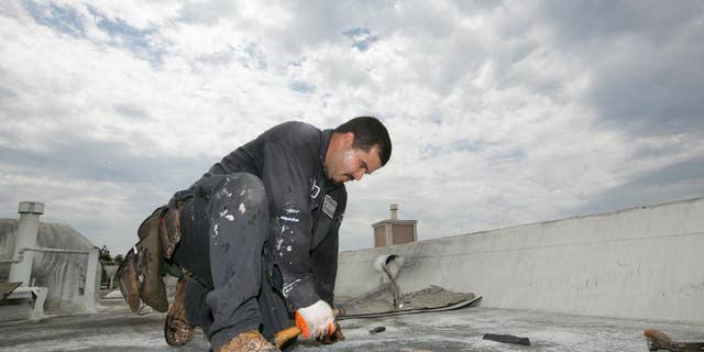 Roofer Joel Camberos with Hull Brothers Roofing & Waterproofing resurface townhomes roofs at the Marina del Rey seaside community of Los Angeles on Tuesday, Aug. 25, 2015. Roofers are reveling in the uptick in business as homeowners ready for the prospect of downpours after four years of dry weather. (AP Photo/Damian Dovarganes)