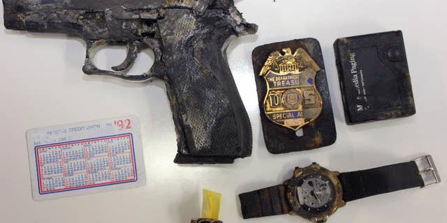 This undated photo provided by the Los Angeles County Sheriff’s Department shows several items, including a handgun and badge of a federal agent, found in a backpack in shallow water by a man fishing at Castaic Lake in northern Los Angeles County. The agent said he got grief from his co-workers after his backpack went overboard during a 1992 boat trip, according to the Los Angeles Times. (AP Photo/ Los Angeles County Sheriff’s Department)