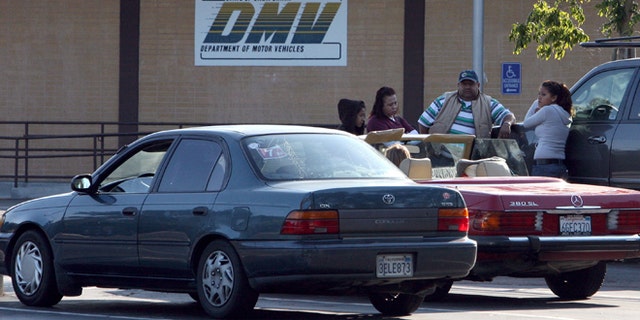 California Department of Motor Vehicles customers sit in the parking lot after finding out that the DMV is closed in Corte Madera, California. (Photo by Justin Sullivan/Getty Images)