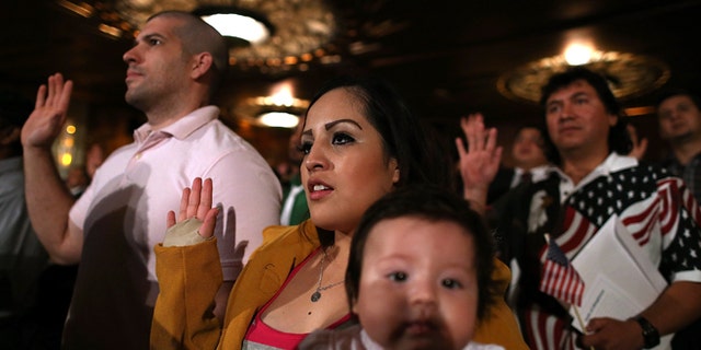 OAKLAND, CA - JULY 30: Karen Franco of Peru holds her four-month old daughter Kyara Franco as she is sworn in as a U.S. citizen during a naturalization ceremony at the Paramount Theatre on July 30, 2013 in Oakland, California. Over 1,100 immigrants became U.S. citizens at the naturalization ceremony. (Photo by Justin Sullivan/Getty Images)