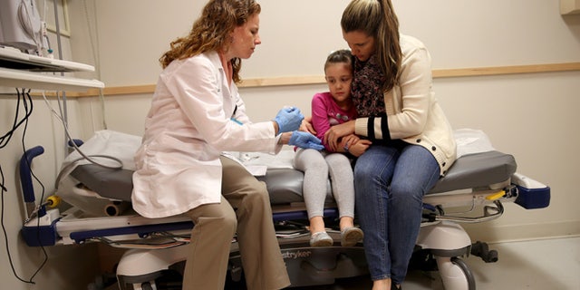 MIAMI, FL - JANUARY 28: Miami Children's Hospital pediatrician Dr. Amanda Porro, M.D prepares to administer a measles vaccination to Sophie Barquin,4, as her mother Gabrielle Barquin holds her during a visit to the Miami Children's Hospital on January 28, 2015 in Miami, Florida. A recent outbreak of measles has some doctors encouraging vaccination as the best way to prevent measles and its spread. (Photo by Joe Raedle/Getty Images)