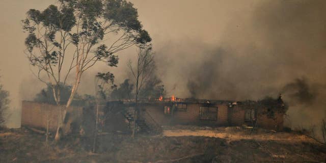 FILE - In this May 15, 2014 file photo, a mountaintop home burns in the Cocos wildfire in San Marcos, Calif. A judge has found a 14-year-old girl guilty of arson for igniting a branch that caused last year's devastating wildfire in San Diego County. Spokesman Steve Walker of the San Diego County District Attorney's office says the girl was found guilty Tuesday, March 24, 2015 of multiple felony counts of arson and one misdemeanor count of unlawfully allowing a fire to escape one's control. Prosecutors say the girl ignited branches amid a spate of wildfires in the county and laughed about it when she told her sister. (AP Photo/Lenny Ignelzi, File)