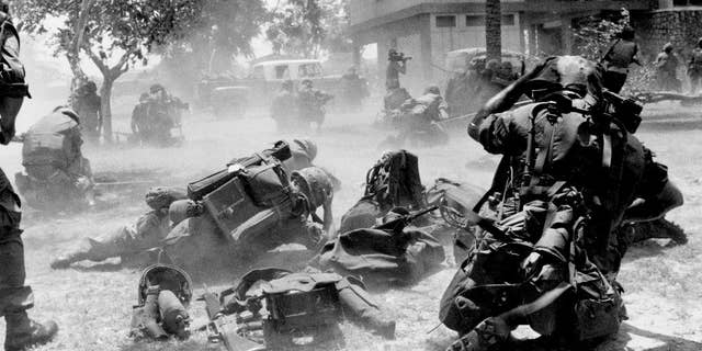 FILE - In this April 13, 1975, file photo, U.S. Marines come under Khmer Rouge fire while they were on the ground near the U.S. embassy during Operation Eagle Pull which evacuated American and embassy personnel in Phnom Penh, Cambodia. Five days after Operation Eagle Pull, the dramatic evacuation of Americans, the U.S.-backed government fell as communist Khmer Rouge guerrillas stormed into Phnom Penh. Nearly 2 million Cambodians - one in every four - would die from executions, starvation and hideous torture. (AP Photo/Tea Kim Heang, File)