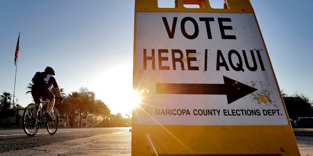 FILE - In this Aug. 30, 2016 file photo, a cyclist rides past a sign directing voters to a primary election voting station early, in Phoenix. Early voting kicks off next week in North Carolina, the first in a two-month run of voting through key swing states where non-whites and young adults could give one of the presidential campaigns a decisive advantage before Election Day. (AP Photo/Matt York, File)
