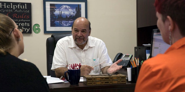 Reverend and Puerto Rican community organization director Robertoluis Lugo Morciglio talks with his colleagues in his office on Friday, Aug.12, 2016. With Puerto Rico's economy in shambles, many are fleeing to the mainland U.S., potentially shifting demographics in some of the country's most critical battleground states. (AP Photo/Dake Kang)