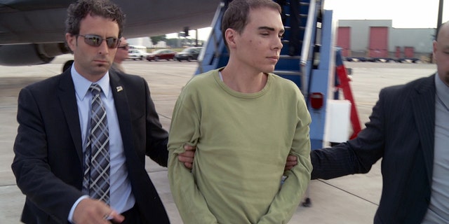 June 18, 2012: In this photo provided by Montreal Police, Luka Rocco Magnotta is taken by police from a Canadian military plane to a waiting van on Monday in Mirabel, Quebec.