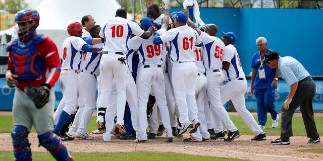 Cuba's Jose Garcia, top center, is mobbed by teammates after hitting a walk off home run off Puerto Rico pitcher Raul Rivera in the ninth inning of the bronze medal baseball game at the Pan Am Games, Sunday, July 19, 2015, in Ajax, Ontario. Cuba won 7-6. (AP Photo/Julio Cortez)