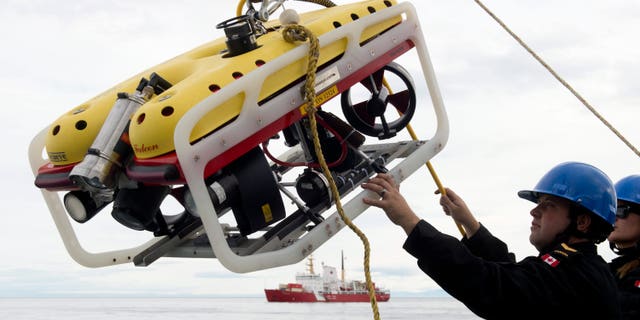 Aug. 24, 2014: A crew member of the HMCS Kingston loads an remote underwater vehicle part of the Victoria Strait Expedition, west of Pond Inlet on the Eclipse Sound.