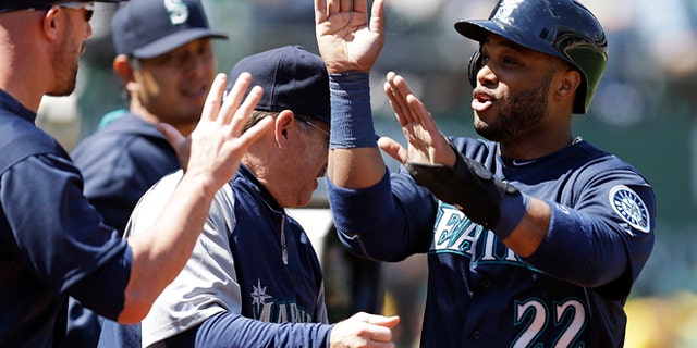 Seattle Mariners' Robinson Cano is congratulated after scoring against the Oakland Athletics in the third inning of a baseball game Sunday, April 6, 2014, in Oakland, Calif. Cano scored on a single by Justin Smoak. (AP Photo/Ben Margot)