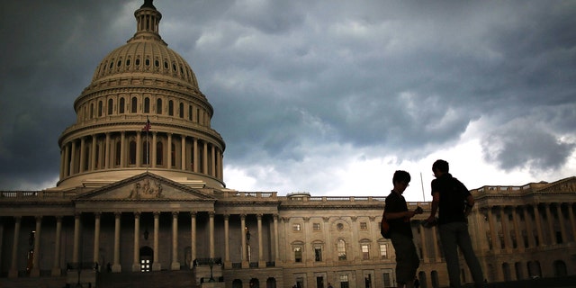 Two men stand on the plaza of the U.S. Capitol Building as storm clouds fill the sky