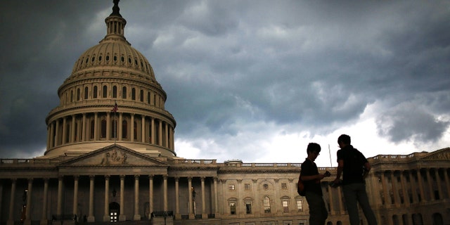 Two men stand on the plaza of the U.S. Capitol Building as storm clouds fill the sky