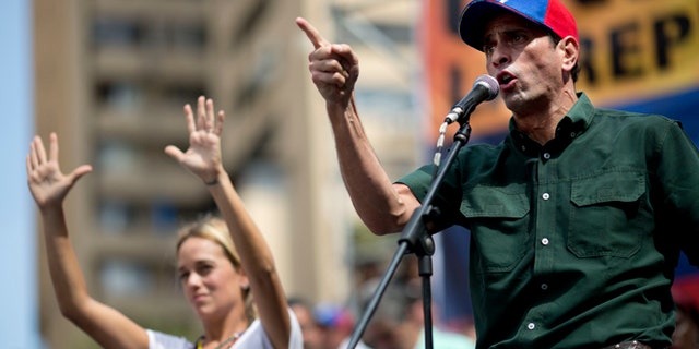 Opposition leader Enrique Capriles delivers a speech next to Lilian Tintori, wife of detained opposition leader Leopoldo Lopez, during a rally in Caracas, Venezuela, Saturday, Feb. 22, 2014. Authorities blamed opposition leader Lopez for fomenting he violence and jailed him on charges including arson and incitement, prompting anger from his supporters at home and criticism from abroad. Supporters and opponents of the government of President Nicolas Maduro are holding competing rallies in the bitterly divided country. (AP Photo/Rodrigo Abd)