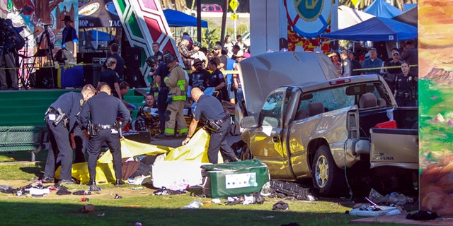 Police cover the bodies of people that were killed when a pickup truck landed on them after it flew off a ramp to the San Diego Coronado Bridge as paramedics prepare to put an injured man on a gurney, background, at Chicano Park in San Diego on Saturday, Oct. 15, 2016. Four people were killed and nine were injured on Saturday after an out-of-control pickup truck plunged off the San Diego-Coronado Bridge and plowed into crowd gathered at a festival below, authorities said.   (Hayne Palmour IV/The San Diego Union-Tribune via AP)