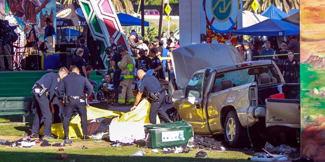 Police cover the bodies of people that were killed when a pickup truck landed on them after it flew off a ramp to the San Diego Coronado Bridge as paramedics prepare to put an injured man on a gurney, background, at Chicano Park in San Diego on Saturday, Oct. 15, 2016. Four people were killed and nine were injured on Saturday after an out-of-control pickup truck plunged off the San Diego-Coronado Bridge and plowed into crowd gathered at a festival below, authorities said. (Hayne Palmour IV/The San Diego Union-Tribune via AP)