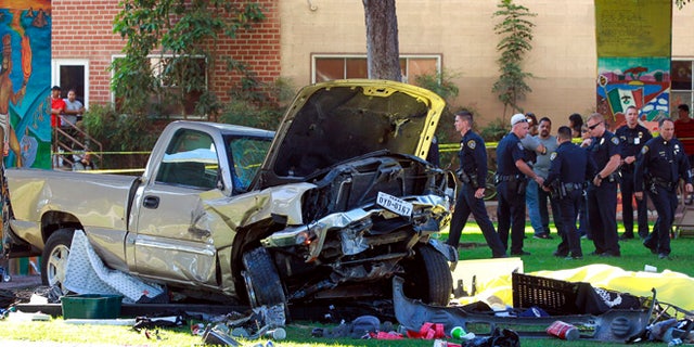Police stand near the pickup truck that landed at Chicano Park in San Diego on Saturday, Oct. 15, 2016.